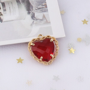 Macro shot of gold-plated heart pendant with faceted red zircon and lace-cut metal edges