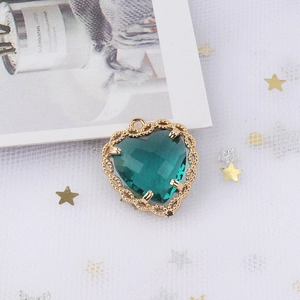 Detail of heart-shaped copper pendant with green zircon and gold textured border