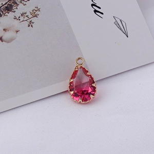 Vue macro d'un pendentif en cristal rose dégradé en forme de goutte et serti doré