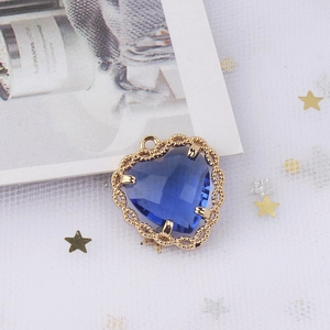 Macro view of blue heart zircon pendant with golden lace filigree for jewelry making