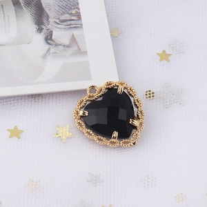 Detail view of heart-shaped pendant with black zircon gemstone and golden mesh frame