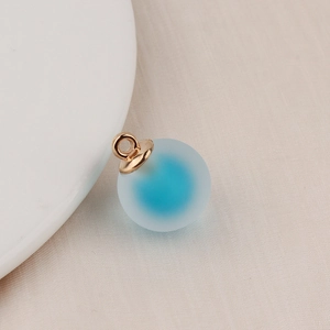 Macro shot of frosted blue gradient bubble bead pendant with gold ring for DIY jewelry making