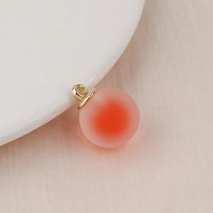 Macro view of gradient orange frosted bubble bead charm with a gold metal loop hook