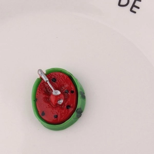 Miniature resin watermelon slice with tiny spoon detail for DIY crafts on ceramic plate