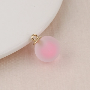 Macro shot of a pink frosted bubble bead with a golden alloy loop for DIY jewelry making