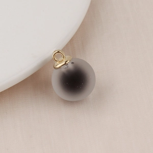 Detail of a frosted gradient bubble bead with a golden metal loop on white fabric