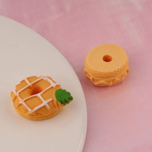 Macro detail of miniature resin pineapple donut and macaron charms for DIY crafts