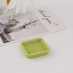 Close-up of miniature light green resin tray with woven rattan texture and flower decor
