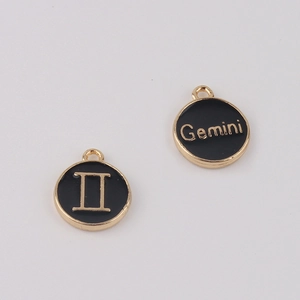 Détail d'un pendentif zodiaque Gémeaux rond avec émail noir et gravure de lettres dorées