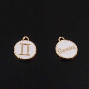 Détail macro du pendentif zodiaque Gémeaux en alliage doré avec émail blanc et symboles