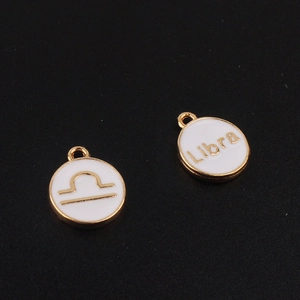 Vue détaillée des pendentifs signe Balance dorés avec finition en émail blanc pur