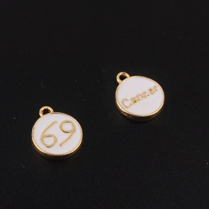 Macro de pendentifs Cancer dorés avec émail blanc sur un fond texturé noir élégant