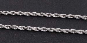 Macro shot of a silver-toned stainless steel rope chain with detailed spiral weave texture