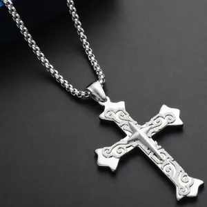 Close-up of a double-layered stainless steel cross pendant with intricate scroll engravings