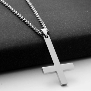Macro shot of polished stainless steel inverted cross pendant on a classic box chain