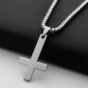 Macro detail of silver inverted cross pendant in brushed titanium steel with box chain