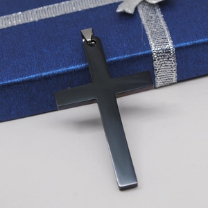 Detailweergave van de gepolijste zwarte roestvrijstalen kruishanger op een geschenkdoos