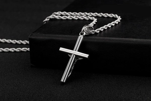 Détail du pendentif croix crucifix argenté avec chaîne corde sur fond noir texturé