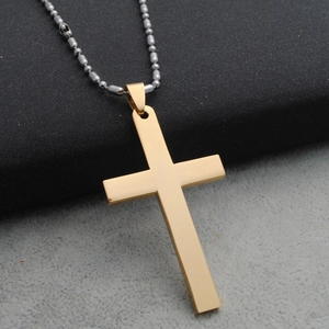 Detailopname van gepolijste gouden kruishanger met zilveren kralenketting op stof