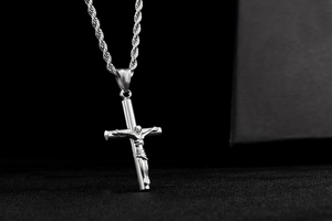 Gros plan détaillé du pendentif crucifix en argent poli et de la chaîne de corde