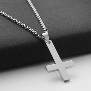 Macro detail of silver stainless steel inverted cross pendant on a beaded metal chain