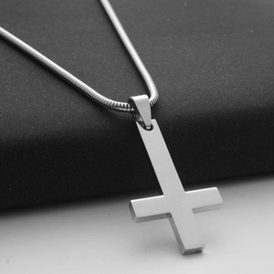 Macro shot of silver St. Peter inverted cross pendant on a sleek snake chain necklace