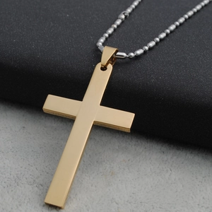 Detail van een gepolijste gouden kruishanger met een zilveren kralenketting op de doos