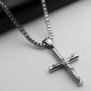 Gros plan d'un pendentif crucifix en acier argenté avec chaîne vénitienne sur cuir noir
