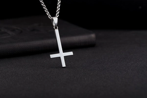 Detailed view of a polished stainless steel inverted cross pendant on a thin silver chain