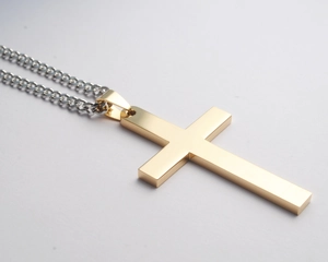 Detail van minimalistische gouden kruishanger met gepolijste zilveren cubaanse ketting