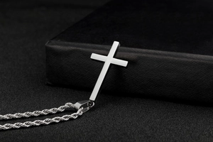 Macro shot of silver stainless steel cross pendant on twist chain with dark background