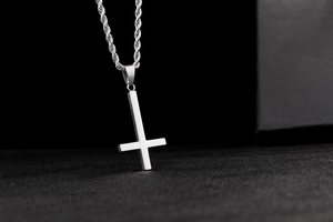 Macro shot of silver inverted cross pendant with sleek stainless steel rope chain