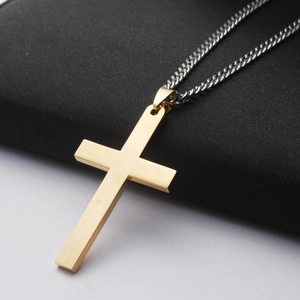 Detail van een minimalistische gouden kruis hanger aan een zilveren Cubaanse ketting