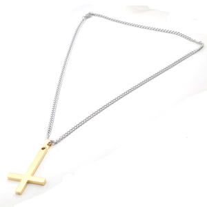 Gros plan d'un collier bicolore avec pendentif croix inversée dorée polie