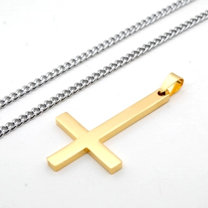 Vue macro d'un pendentif croix inversée dorée avec collier chaîne cubaine en acier