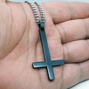 Collier croix inversée noir mat avec chaîne gourmette argentée porté sur la main