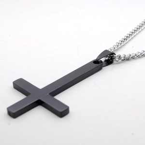 Gros plan d'un pendentif croix inversée noir mat avec une chaîne en acier inoxydable
