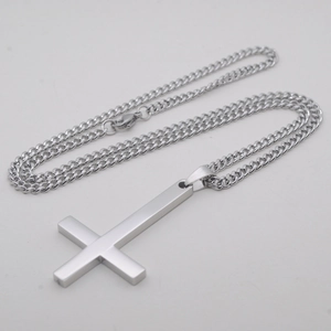 Détail du pendentif croix inversée argentée avec finition mate et chaîne gourmette