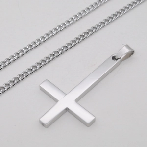Détail du pendentif croix poli en acier inoxydable argenté sur une chaîne gourmette