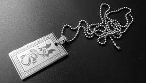 Gros plan d'un motif de dragon gravé au laser sur un pendentif rectangulaire en acier