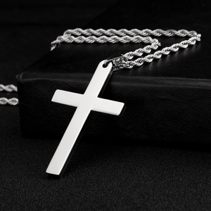 Detailopname van een gepolijste zilveren kruishanger met touwketting op zwart leer