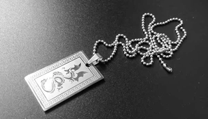 Vue macro d'un totem de dragon gravé sur un pendentif carré en acier inoxydable