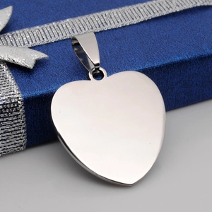 Polished heart-shaped stainless steel pendant on a blue textured gift box