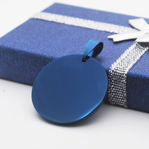 Primer plano de un colgante circular azul de acero inoxidable sobre una caja de regalo
