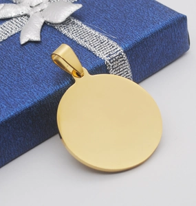 Primer plano de un colgante redondo de acero inoxidable dorado en una caja de regalo