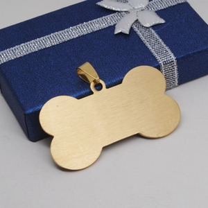 Detailed macro shot of golden bone-shaped metal pet tag with brushed stainless steel finish