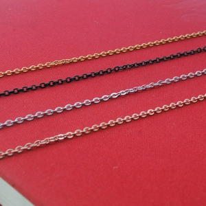 Macro shot showing thin cross chains in gold, black, silver, and rose gold on a red background