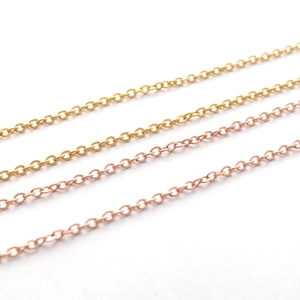 Macro detail of gold and rose gold stainless steel O-chain necklaces on white background