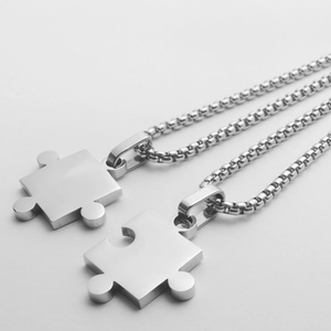 Nahaufnahme der ineinandergreifenden Puzzle-Pärchenhalsketten aus mattem Edelstahl