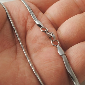 Polished silver stainless steel snake chain necklace held in hand showing lobster clasp